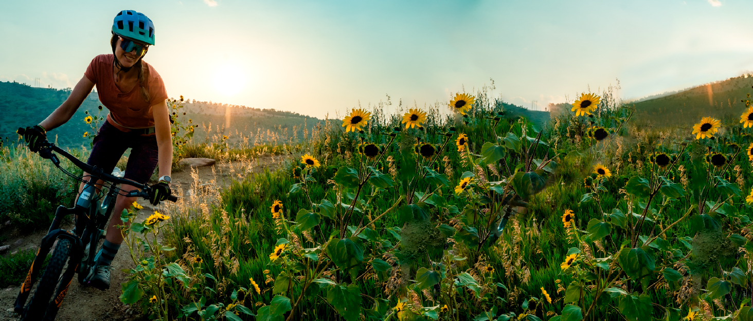 Tailwind Nutrition Endurance Fuel, Carbohydrate & Electrolyte Sports Drink Mix Powder, Gluten-Free, Vegan, Grape, 50 Servings A woman smiling while biking through a field of sunflowers.