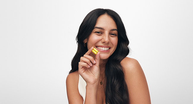 HUM Best of Berberine Supplement 1200mg, Pure Potency for Metabolic Wellness, Gut Health, Pure Berberine Supplements Enhanced with BioPerine for Maximum Absorption, 60 Capsules Smiling woman holding yellow capsule from HUM Best of Berberine supplement